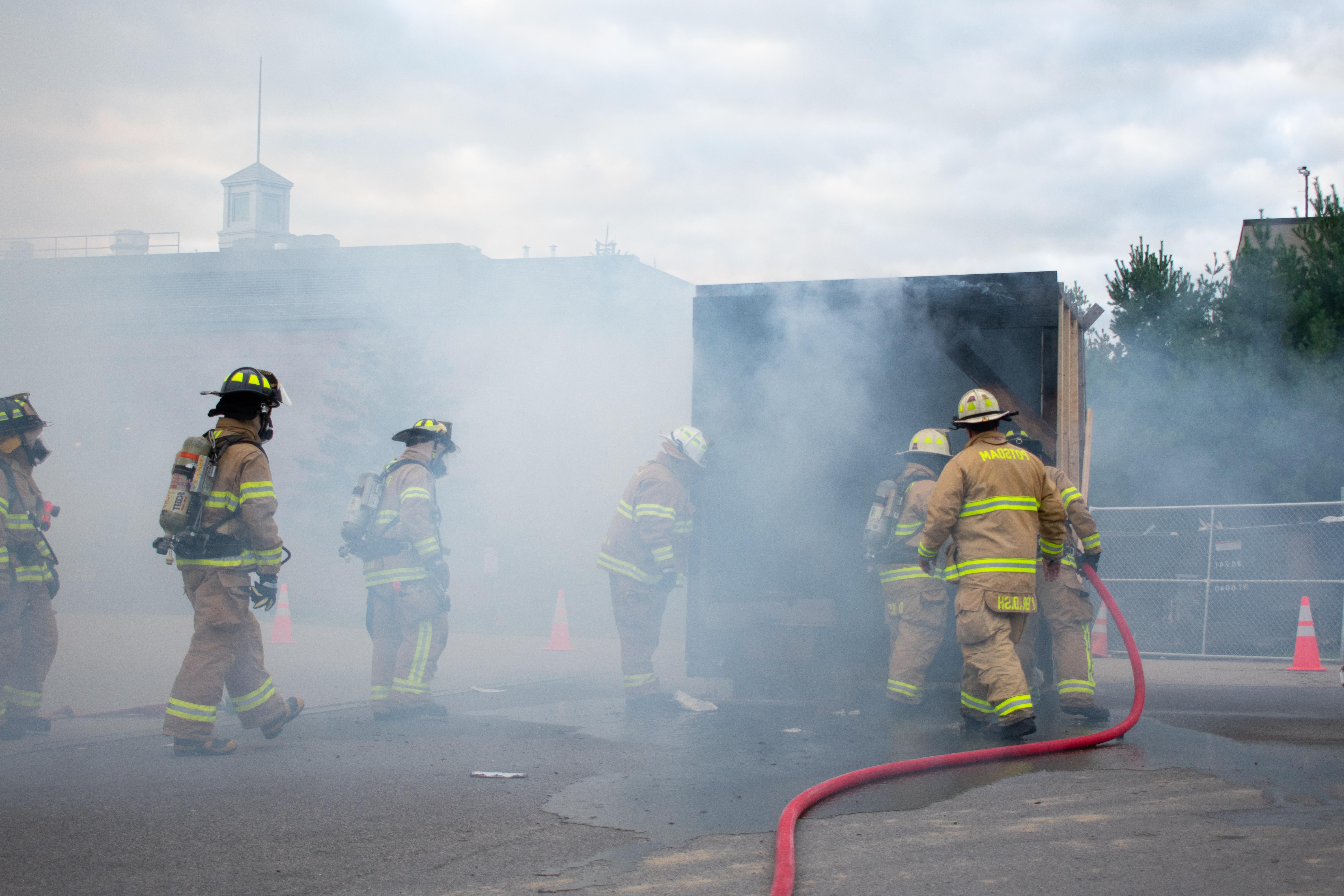 几名消防员围在烟雾弥漫的模拟宿舍周围.